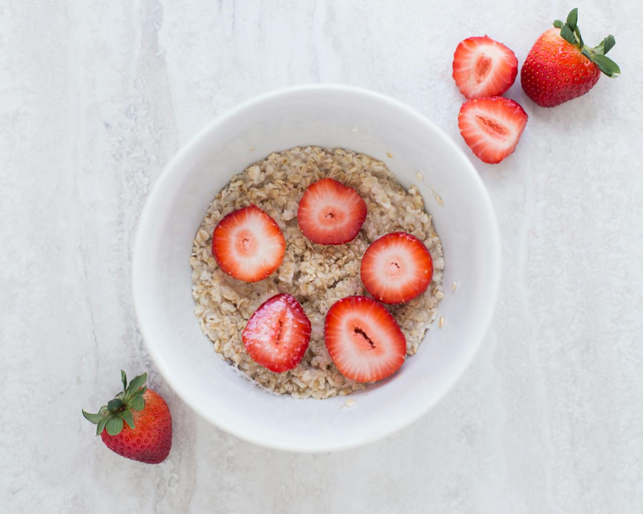 A fresh and nutritious breakfast bowl featuring oats topped with sliced strawberries.